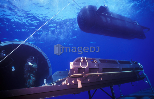 A SEAL Delivery Vehicle hovers above the Dry Deck Shelter next to the outer hangar door.