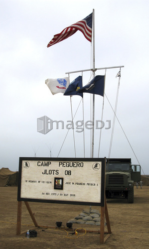 Camp Peguero sign and central flag pole for the Navy, Army and Marine forces camp site.