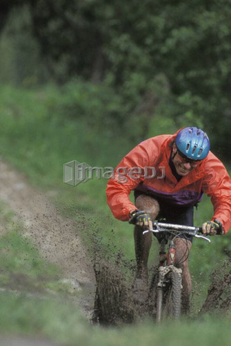young man mountain biking through mud near Fernie, BC, Canada