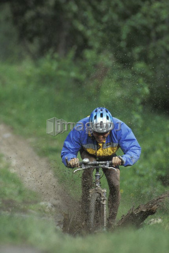 young man mountain biking through mud near Fernie, BC, Canada