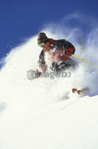 Young man skiing fresh powder on steep slope at Island Lake Resort, Fernie, British Columbia, Canada.