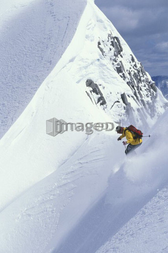 Young man skiing fresh powder on steep slope at Island Lake Resort, Fernie, British Columbia, Canada.
