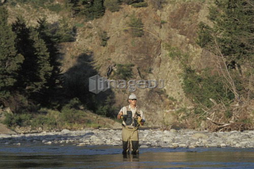 Young man fly fishing on Oldman river in southern  Alberta, Canada.
