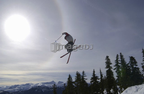 Skier jumping into the sun with skis crossed, Courtenay, B.C.