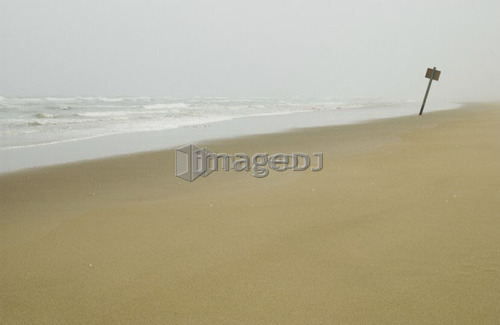 Sign on flat sandy beach with mist in the background, Reedsport, Oregon