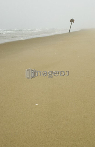 Sign on flat sandy beach with mist in the background, Reedsport, Oregon