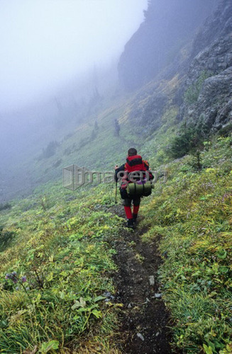 Man (25-30) descending a mountain trail with a backpack on Port Alberni, Vancouver Island, B.C.
