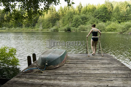 Woman (20-25) walking across a dock with a rowboat on it in a swimsuit, Victoria, Vancouver Island, B.C.