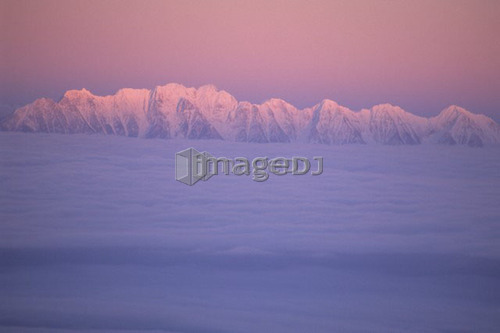 Mountain ridge called the Steeples in evening light with cloud inversion, East Kootenays, B.C.