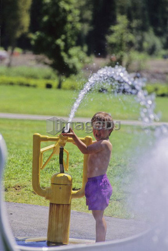Boy, 3, plays with water sprayer at water park, Pemberton, B.C.