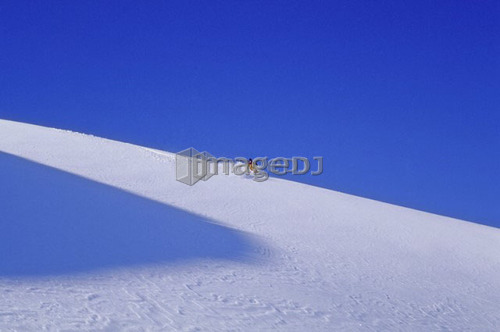 Heli-skier on clean mountain glacier, blue sky, Pemberton Ice Cap, B.C.