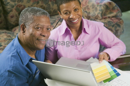 African American couple with paint swatches, laptop and building plans, B.C.
