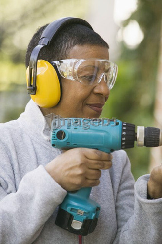 African American woman using a hand drill, B.C.