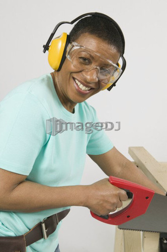 African American Woman Doing Home Improvement, Cutting Lumber With a Hand Saw, B.C.