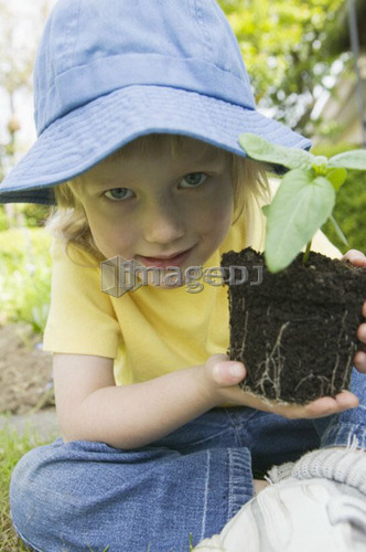Young Girl Holding a Bedding Plant Showing Dirt and Roots