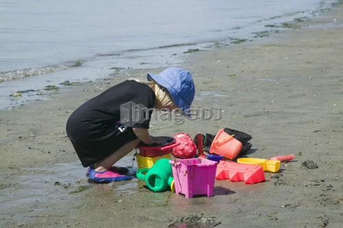 Sidney Spit Marine Park, BC, Canada. 5 year old girl playing with beach toys