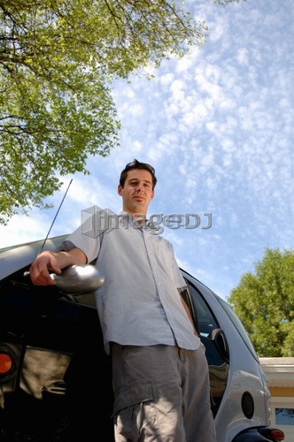 Young man leaning against smart car, Regina, Saskatchewan