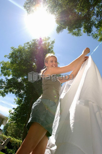 Young woman hanging laundry on clothesline/sunflare, Regina, Saskatchewan