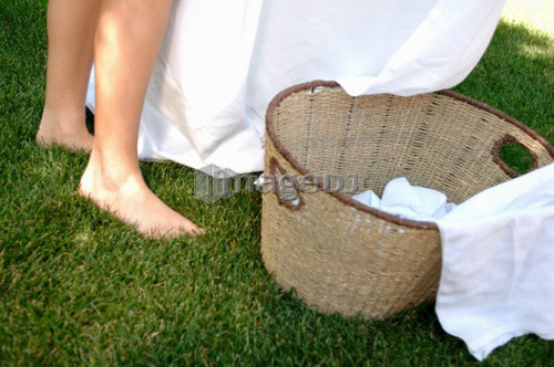 Woman's feet in grass with laundry basket, Regina, Saskatchewan