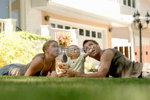 Young man & woman playing with baby in grass, Regina, Saskatchewan