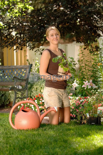 Young woman watering flowers/planting, Regina, Saskatchewan