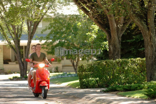 Teenage boy and girl driving red vespa, Regina, Saskatchewan
