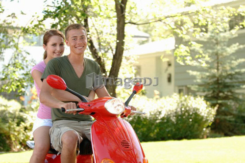 Teenage boy and girl driving red vespa, Regina, Saskatchewan