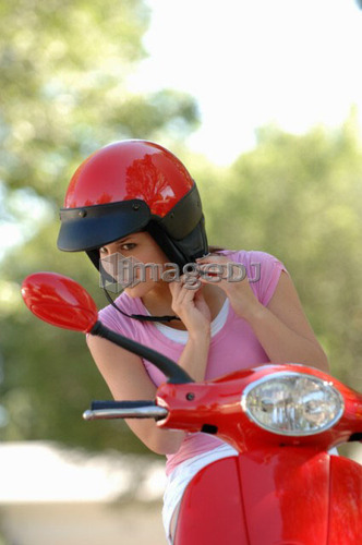 Young girl fastening helmet on red vespa, Regina, Saskatchewan