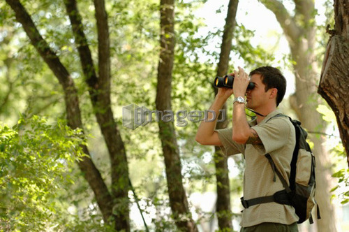 Young man in woods w/binoculars, Regina, Saskatchewan