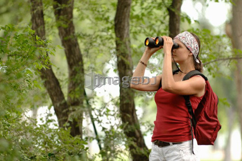 Woman in woods with binoculars, Regina, Saskatchewan
