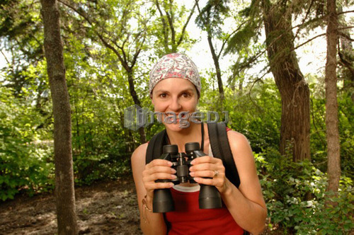 Woman in woods with binoculars, Regina, Saskatchewan