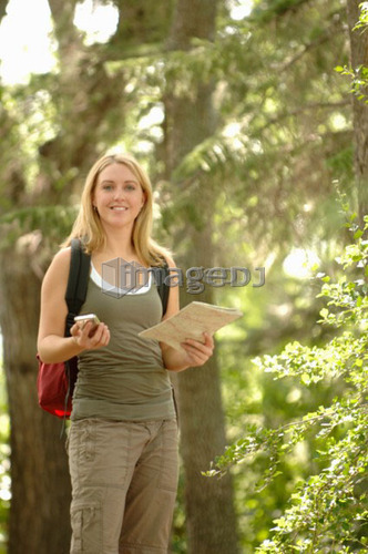 Young woman with gps type device and map in woods, Regina, Saskatchewan