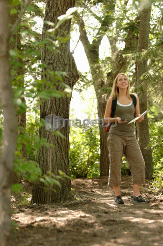 Young woman with gps type device and map in woods, Regina, Saskatchewan