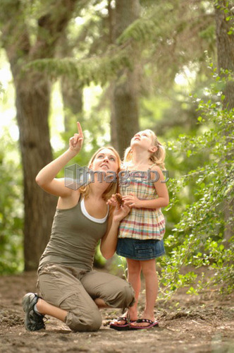 Young woman and child in woods looking at scenery, Regina, Saskatchewan