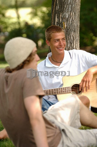 2 young guys playing guitar in park, Regina, Saskatchewan