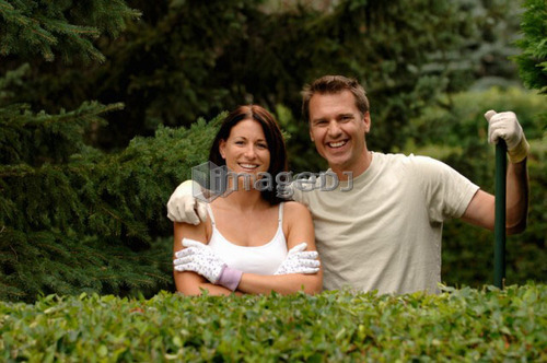 Couple posing behind hedge, Regina, Saskatchewan