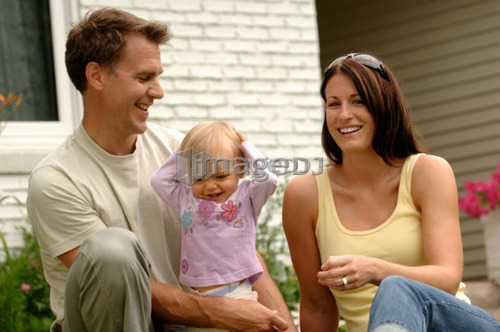 Young couple w/baby in front of house, Regina, Saskatchewan