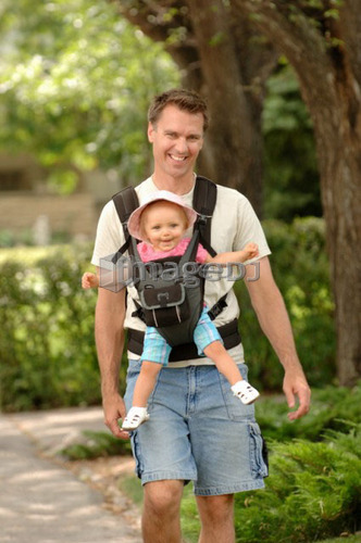 Man walking down street carrying baby in snuggly, Regina, Saskatchewan