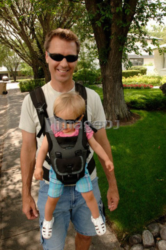 Man walking down street carrying baby in snuggly, Regina, Saskatchewan