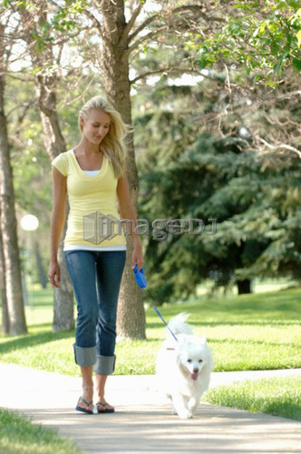 Young woman walking dog in park, Regina, Saskatchewan