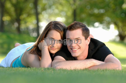 Boy and girl teenagers in grass at park, Regina, Saskatchewan