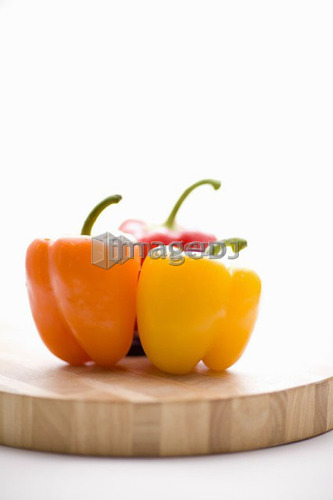 Yellow, orange and red peppers on butcher block cutting board in profile