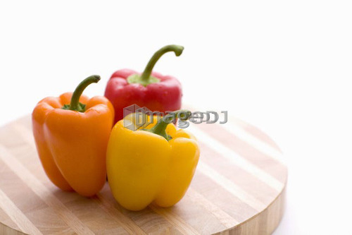 Yellow, orange and red peppers on butcher block cutting board