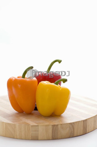 Yellow, orange and red peppers on butcher block cutting board