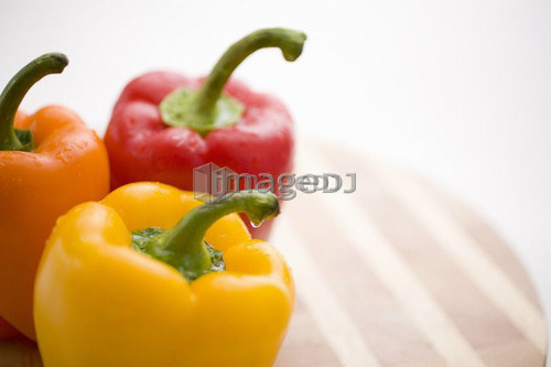 Yellow, orange and red peppers on butcher block cutting board