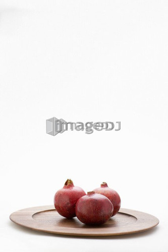 3 pomegranates on wooden plate