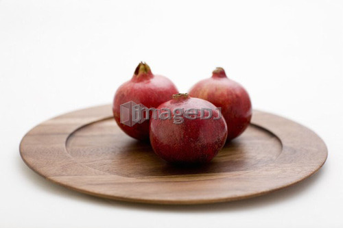 3 pomegranates on wooden plate