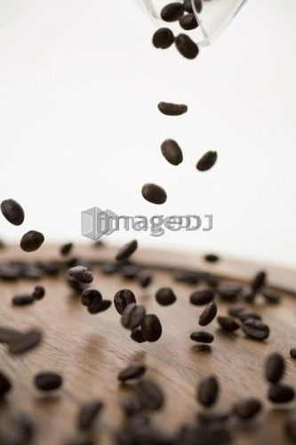 Coffee beans dropping onto wooden plate