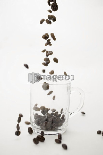 Coffee beans falling into clear coffe cup
