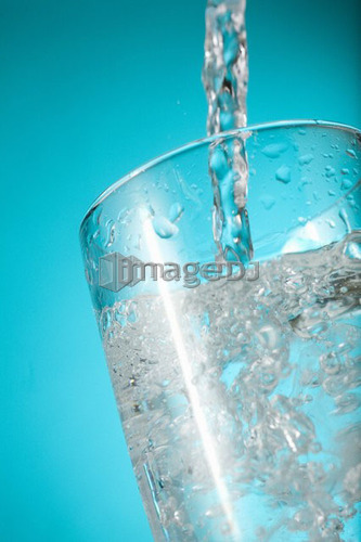 Water pouring into clear glass, nearly full